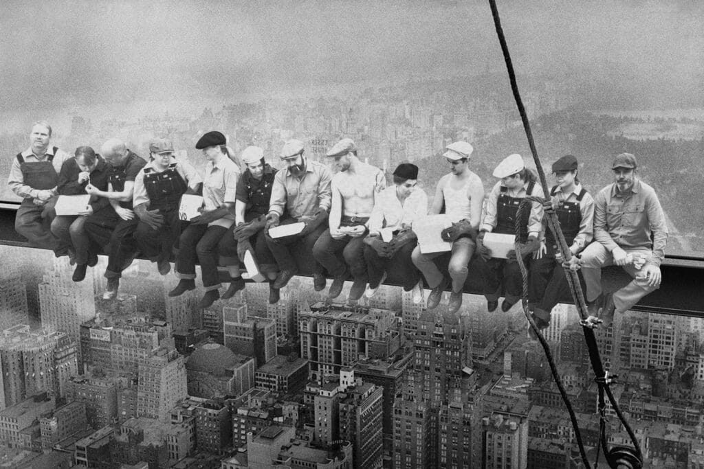 Architect and builder team in costume emulating the black and white lunch atop a skyscraper photo from 1932