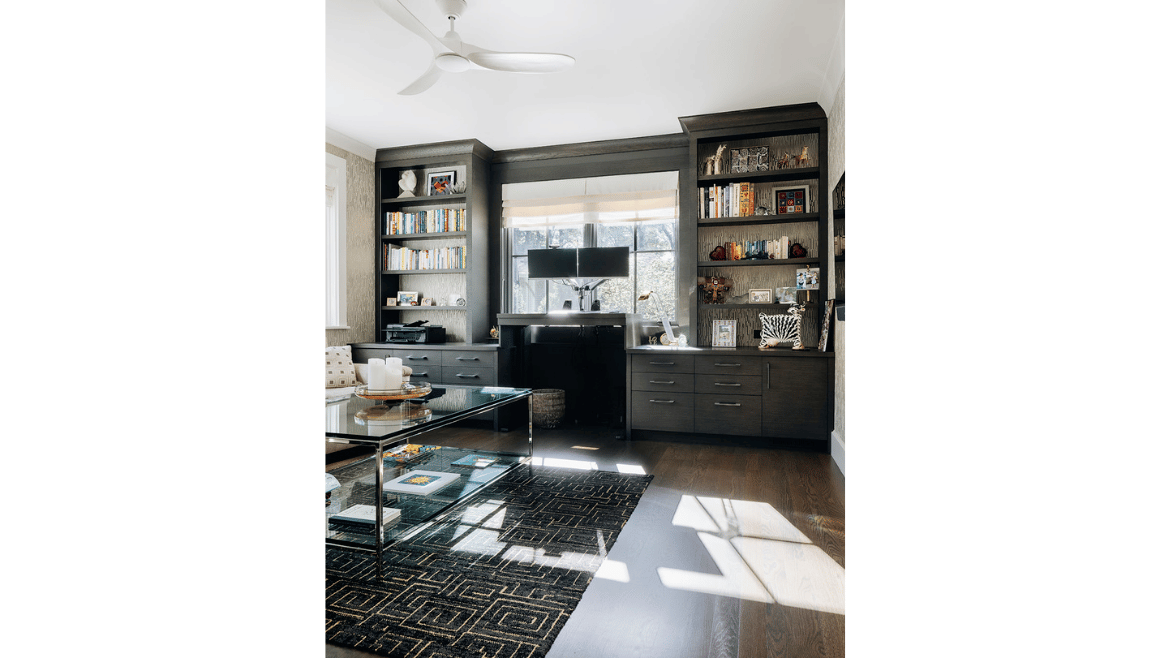 Modern mountain craftsman style home office with dark gray custom built-in shelves, standing desk and seating area with glass coffee table