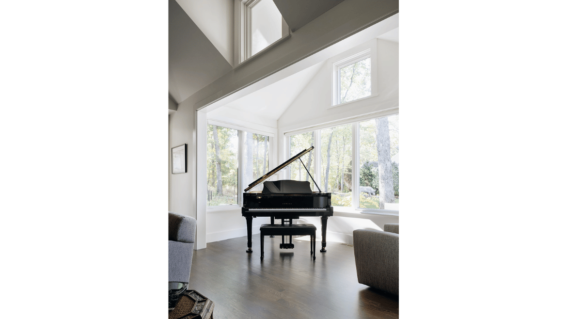 Modern mountain craftsman home sunroom with large windows, wood floors and black baby grand piano