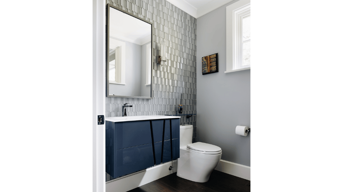 Stylish powder room featuring custom, floating navy blue vanity, full-wall tiling, sconces and a Toto toilet.