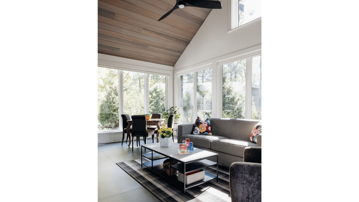 Modern mountain craftsman home sunroom with walls of windows, wood-paneled cathedral ceiling