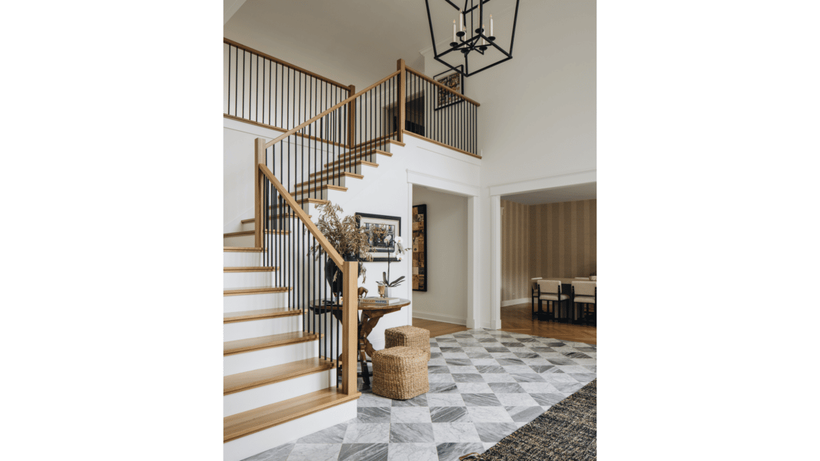 Foyer with L-shaped stairs of natural wood treads and handrail, checkerboard style gray tile floor, large hanging light fixture