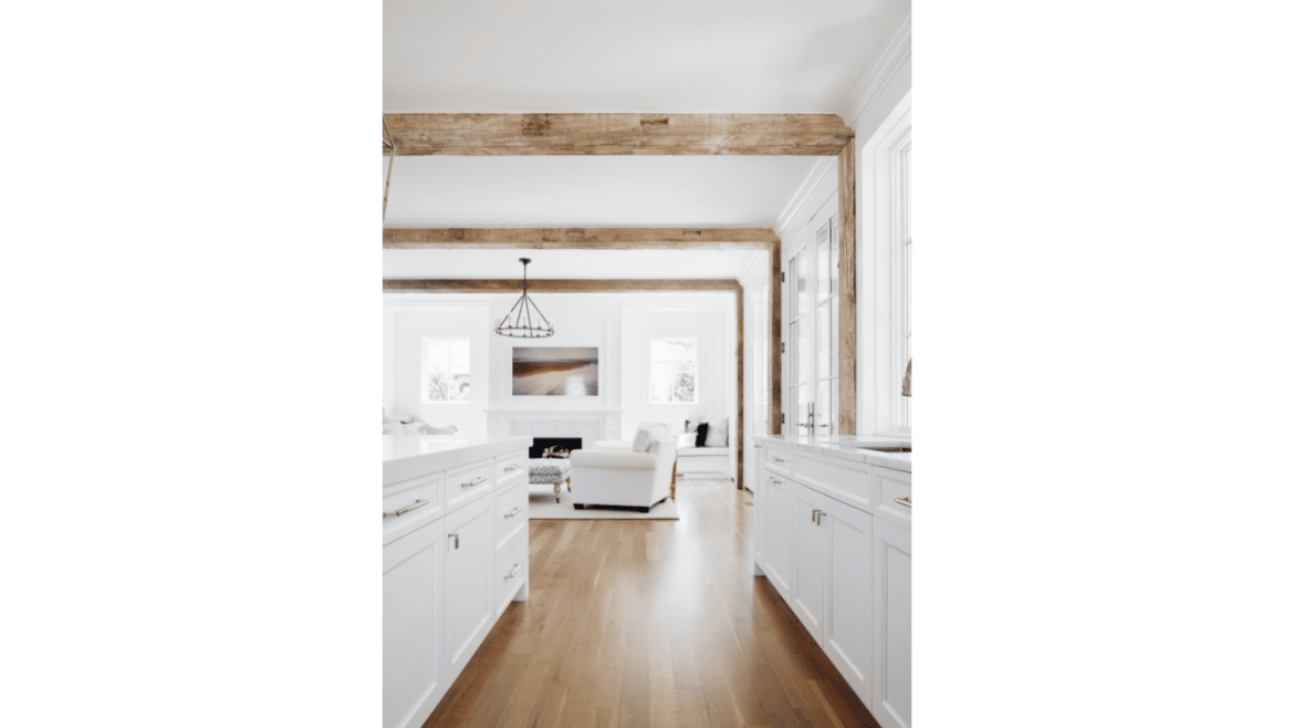 Modern farmhouse white kitchen, open concept to living area with accent reclaimed wood beam ceiling and columns