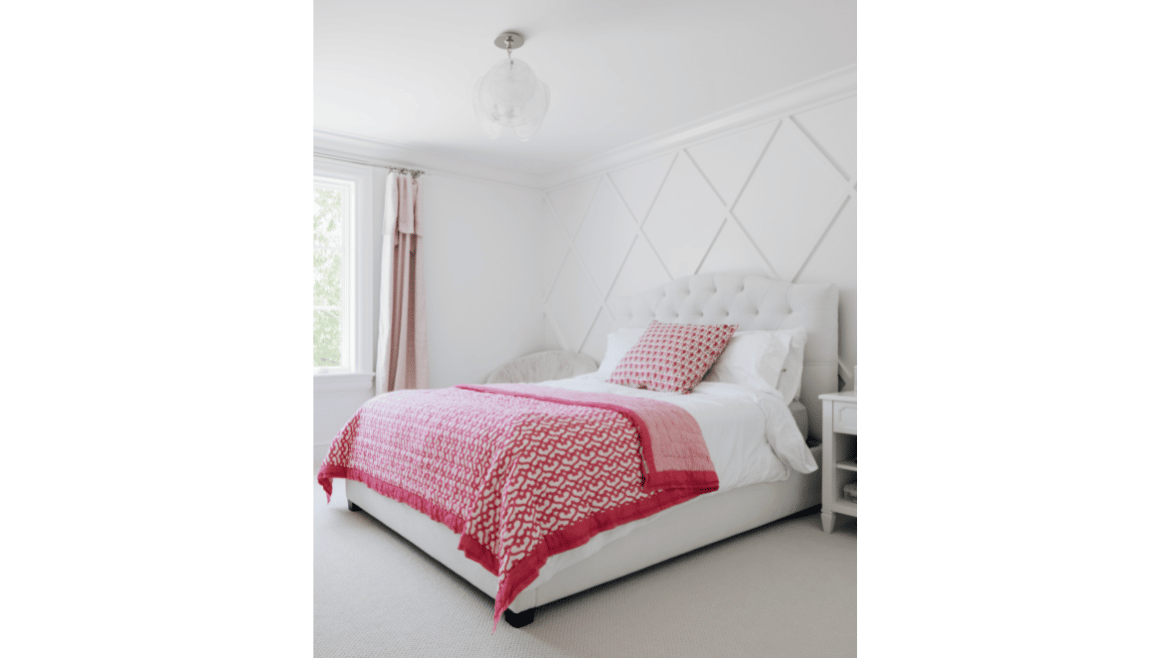 Modern farmhouse white bedroom with paneled wall and red bedding accents with white tufted headboard