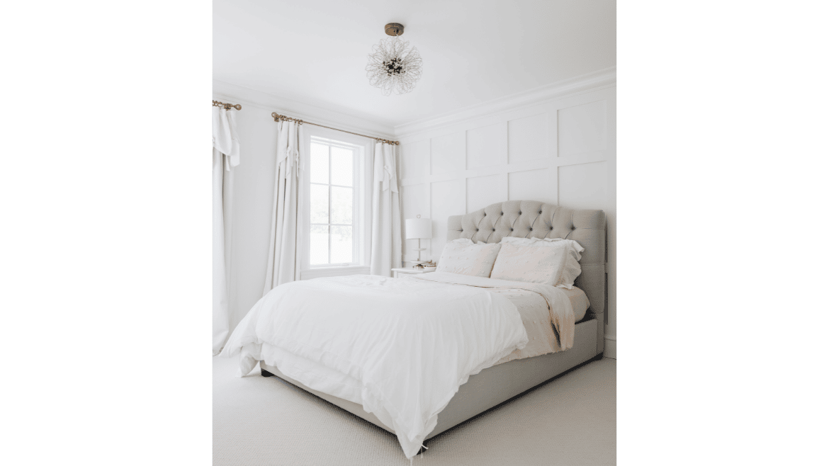Modern farmhouse white bedroom with square paneled wall, white drapes and bedding with tufted headboard