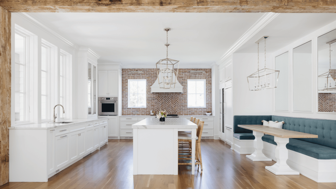 Modern farmhouse white kitchen, large center island and banquette, beam ceiling and white-washed red brick backsplash