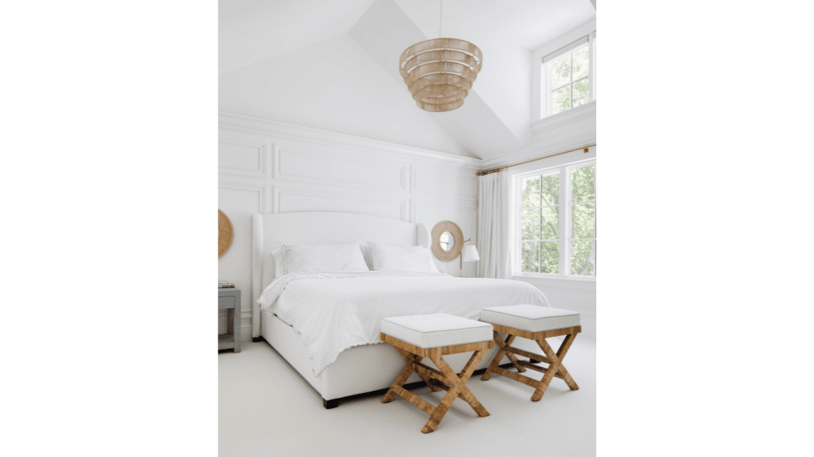 All white primary bedroom with paneled wall, white bedding and furniture with two story window