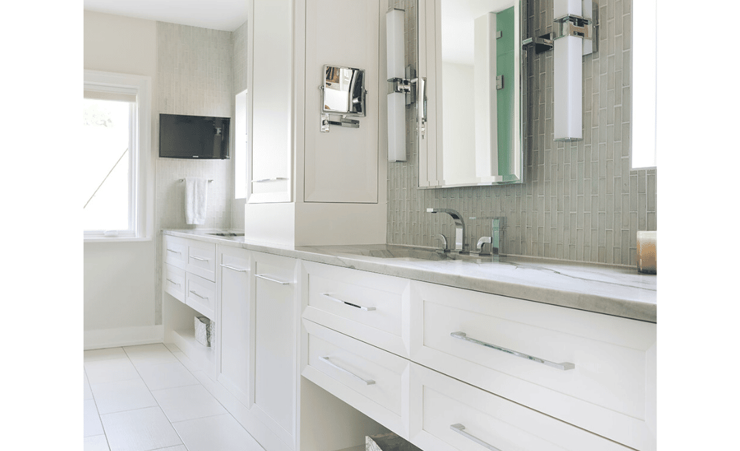Double sink primary bathroom vanity with separate areas framed by white built-in cabinetry