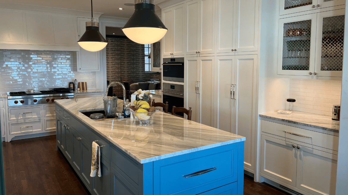 White kitchen with bright blue island, rounded hanging light fixtures, gray and white counter