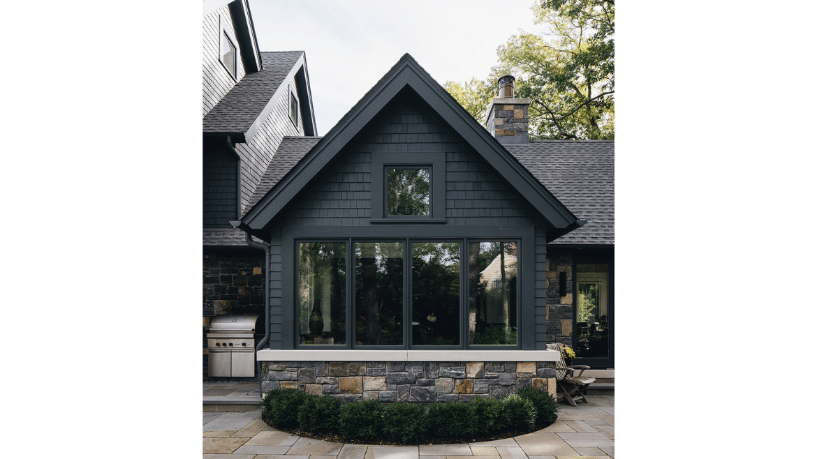 Modern craftsman home porch exterior with dark siding and stone apron