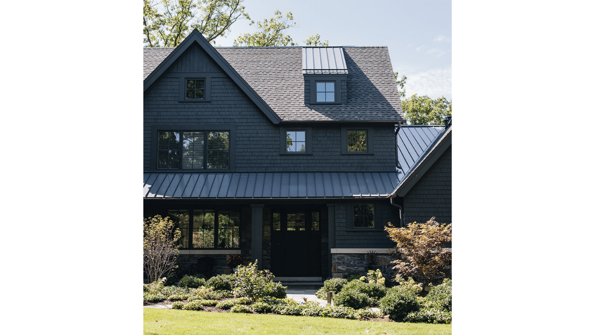 Modern craftsman home front door exterior with dark siding, metal roofing and stone apron