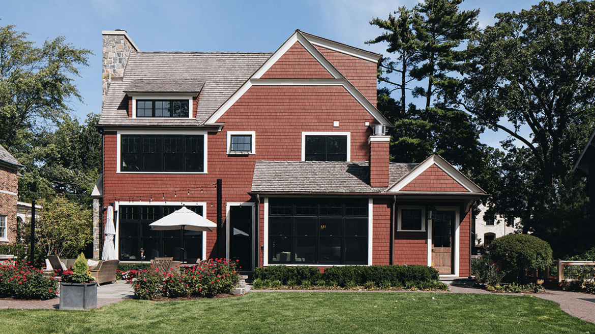 Back exterior of contemporary shingle style home with red siding and transom windows