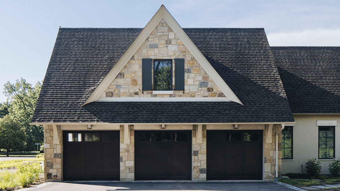 Traditional French Country 3-car Garage with stone detailing and dark brown doors