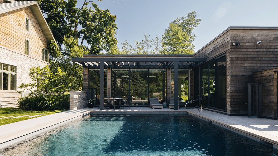 Wilmette Modern pool house with recycled ash siding, pergola-covered pool deck, sliding doors and dark tiled rectangular pool
