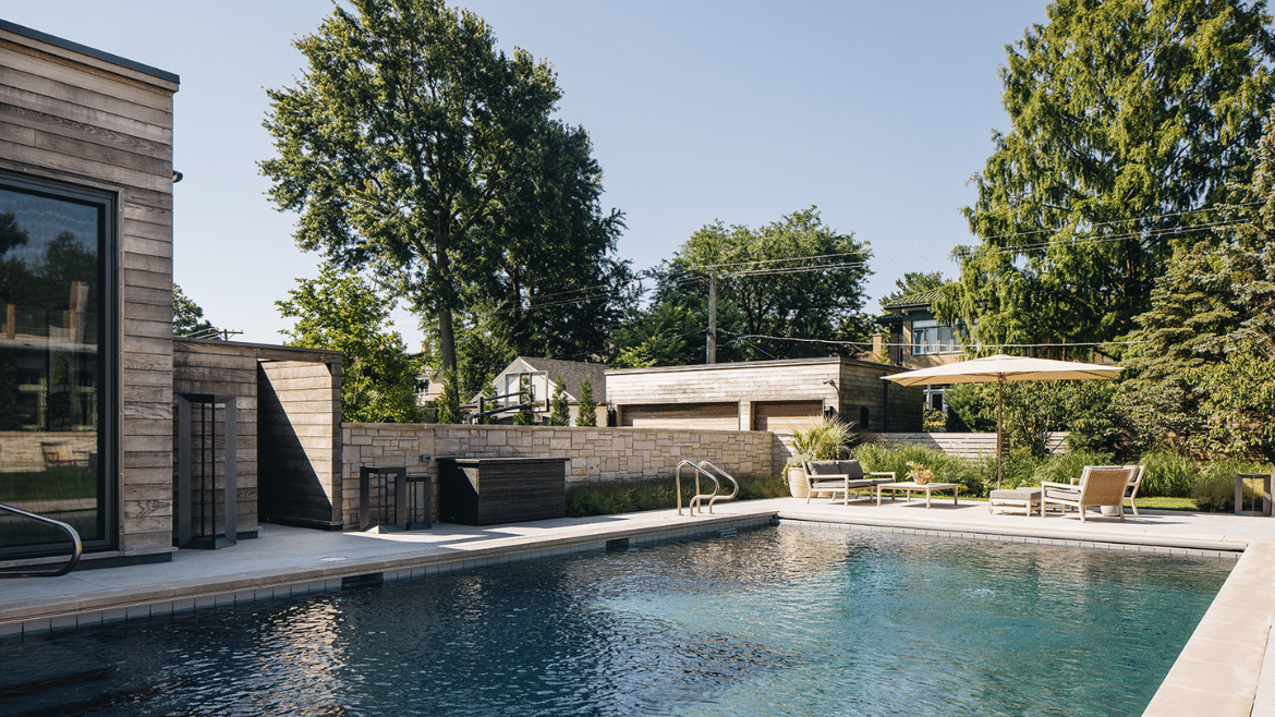 Wilmette backyard pool with outdoor shower, seating area, stone wall and dark tiled pool