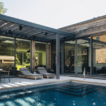 Wilmette Modern pool house with recycled ash siding, pergola-covered pool deck, sliding doors and dark tiled pool